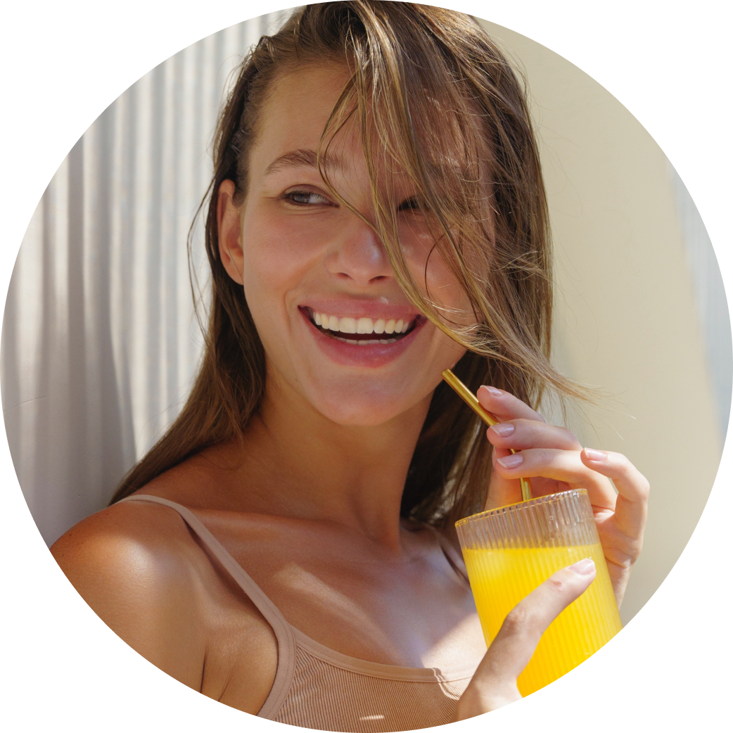 A young woman holding a glass filled with diluted collagen, looking refreshed and healthy